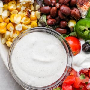 Close-up image of a small bowl of creamy southwest dressing in a large bowl of a santa fe salad.
