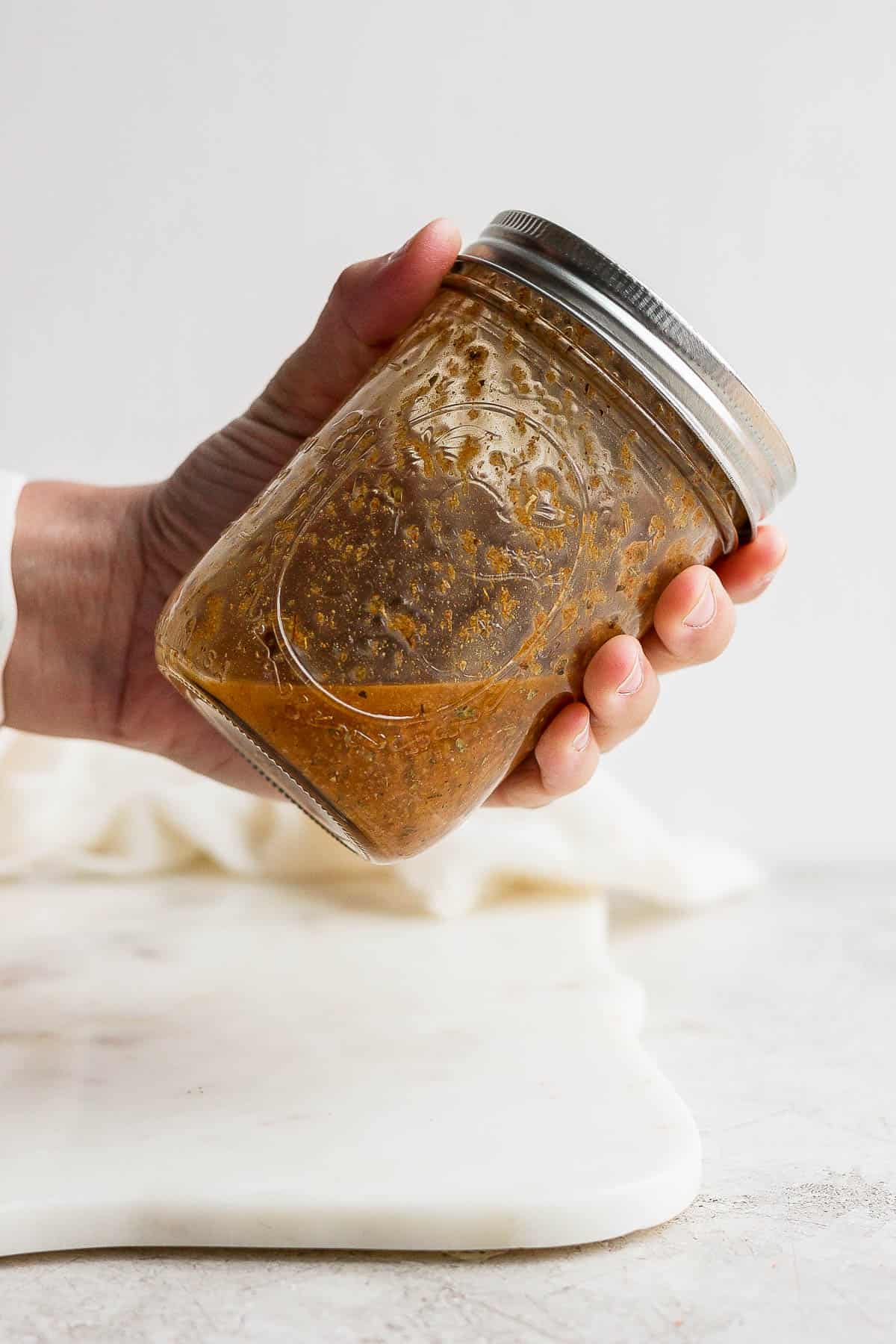 A hand shaking the mason jar with the southwest vinaigrette dressing.
