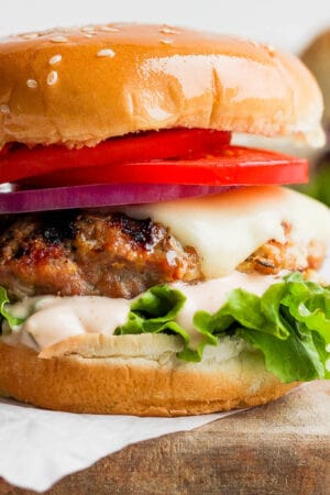 A turkey burger with lettuce, cheese and tomato.