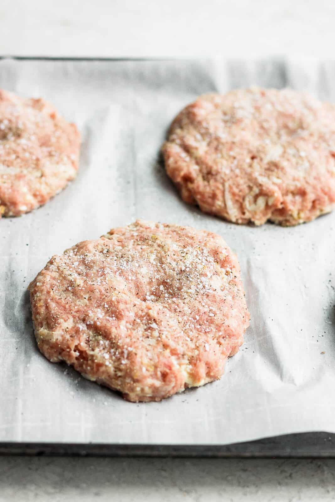 Turkey burger patties on a parchment-lined baking sheet.
