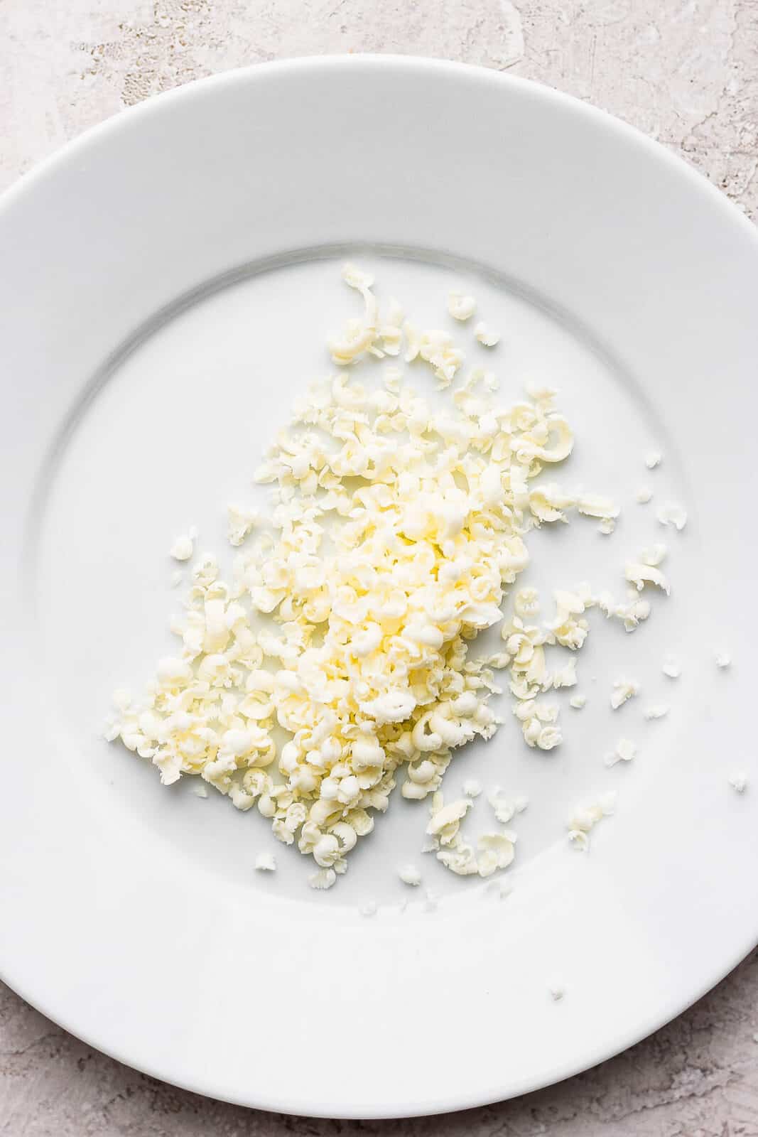 Frozen, grated butter on a white plate.
