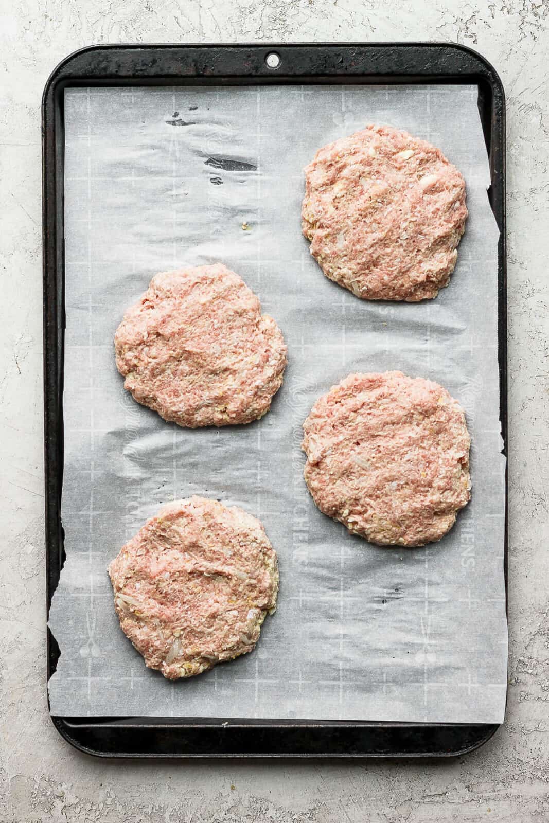Turkey patties on a parchment-lined baking sheet.