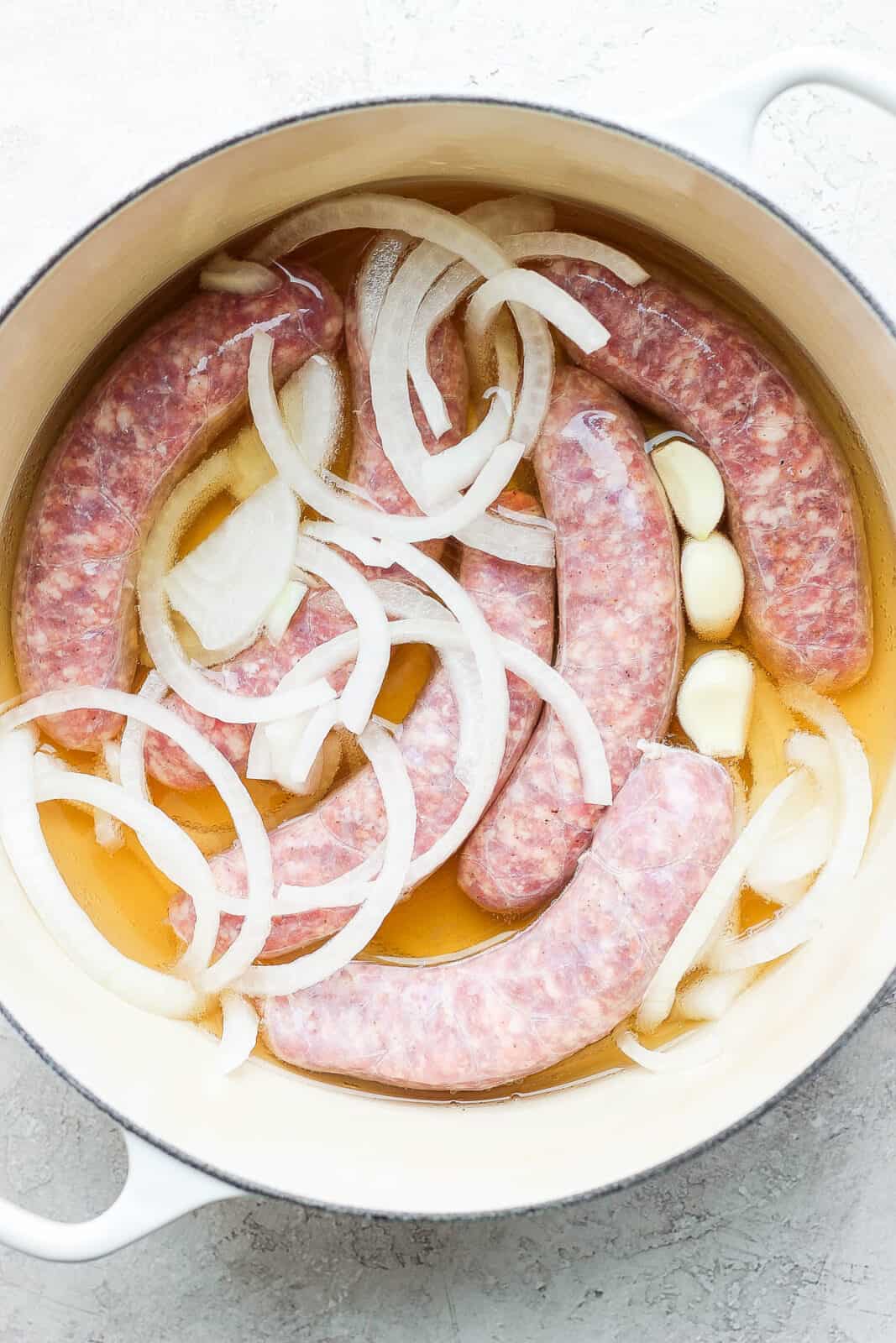 Brats in a dutch oven with beer, onion, and garlic.