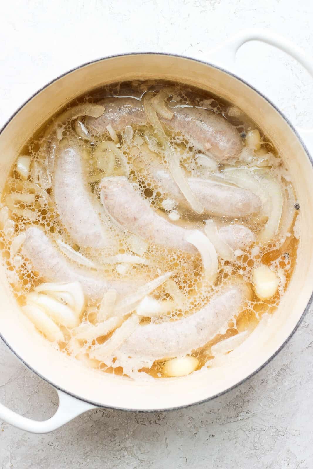 Brats boiling in beer, onion, and garlic.