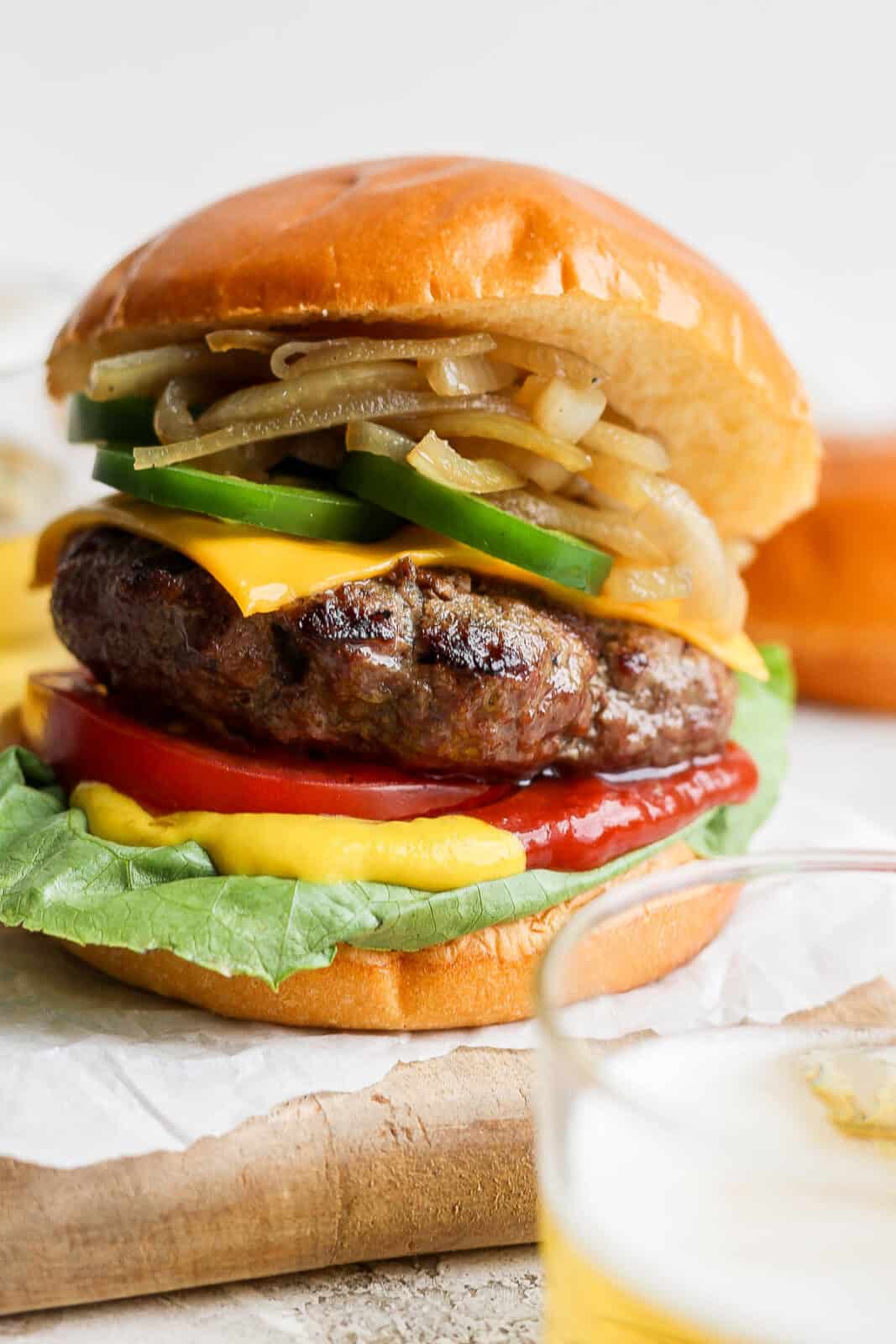 A beer burger on a bun with onions and jalapeno. 