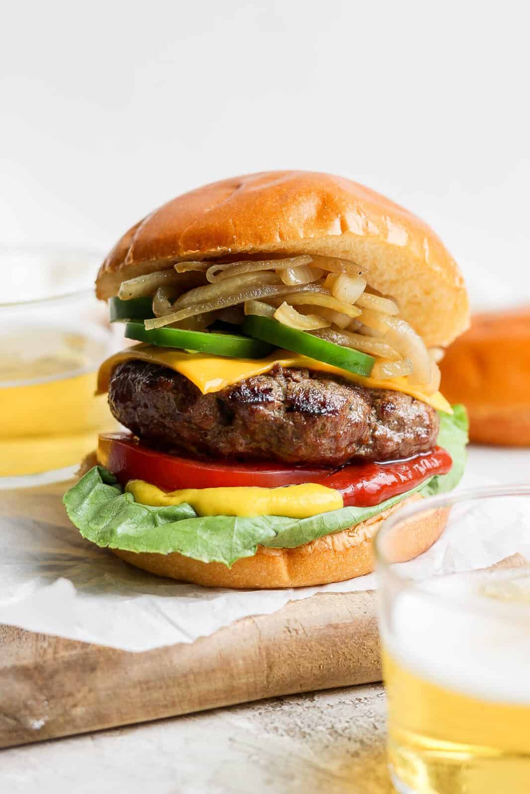 A beer burger on a bun with onions and jalapeno. 