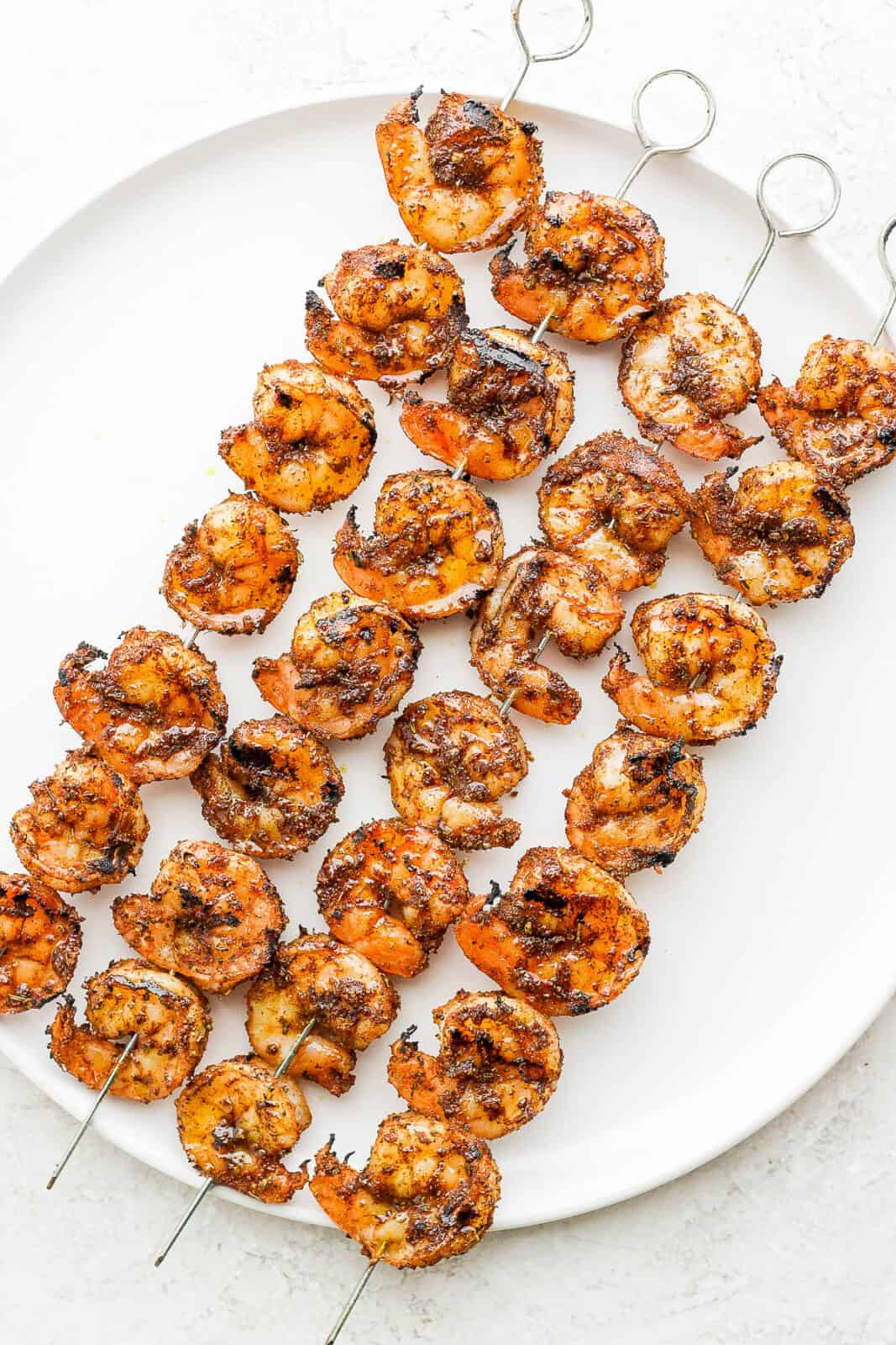 Cooked blackened shrimp on skewers.