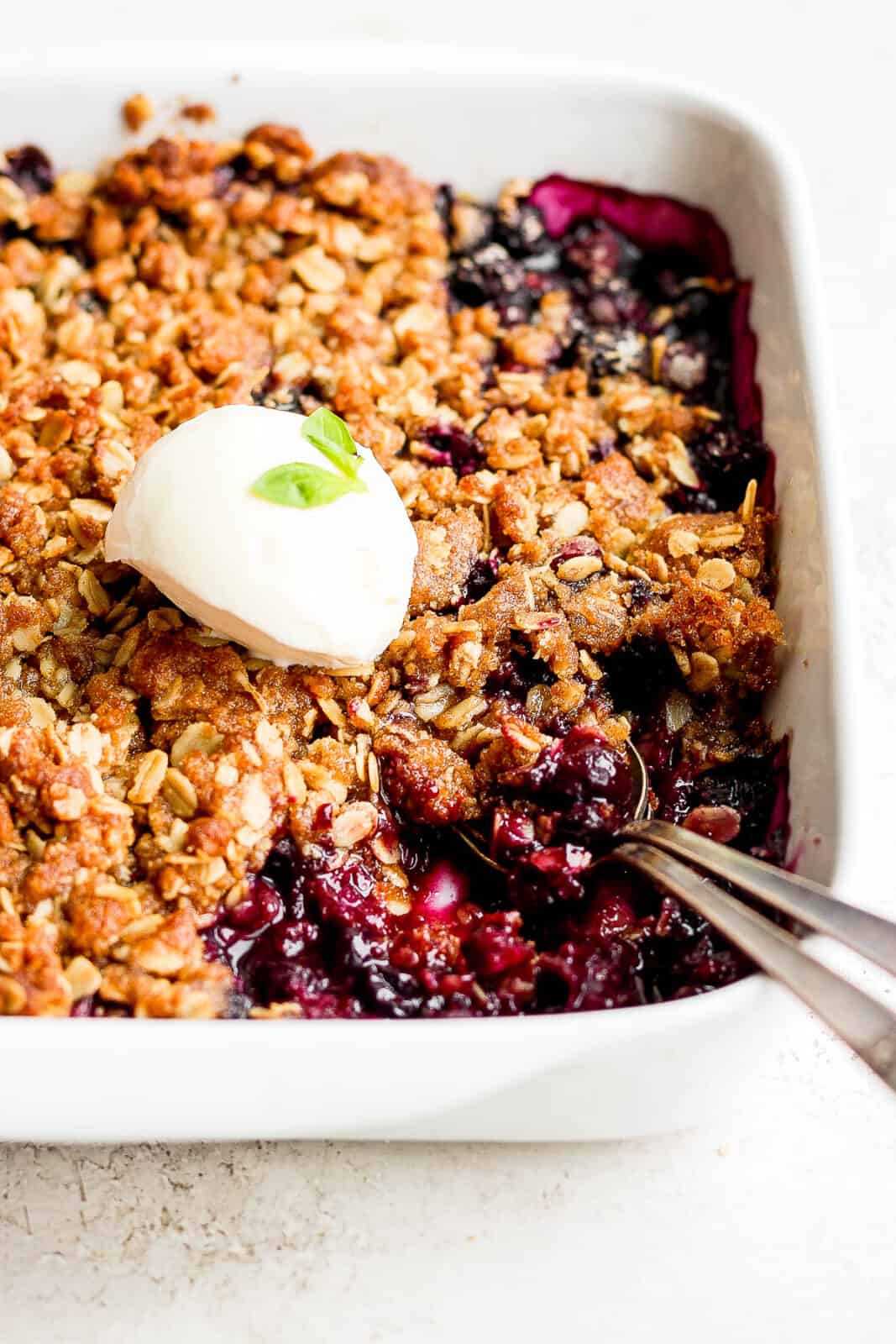 Blueberry crisp and ice cream with two spoons.