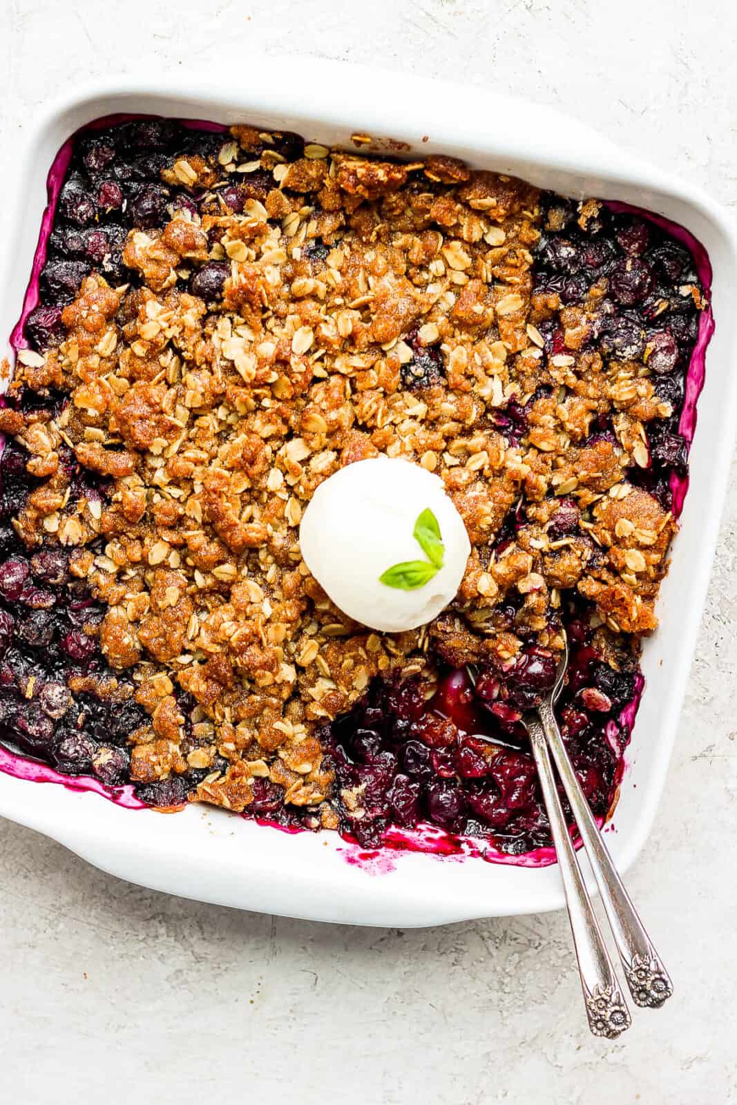 A quick and easy blueberry crisp with a scoop of vanilla ice cream on top.