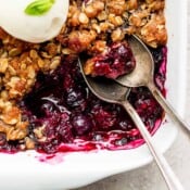 Close up shot of the corner section of 9x9 pan of blueberry crisp with two spoons sticking out.