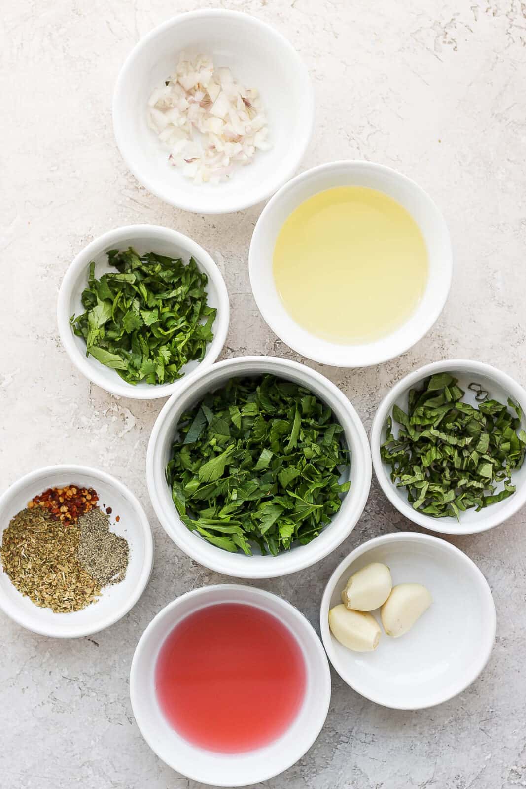 Ingredients for chimichurri sauce in separate bowls.