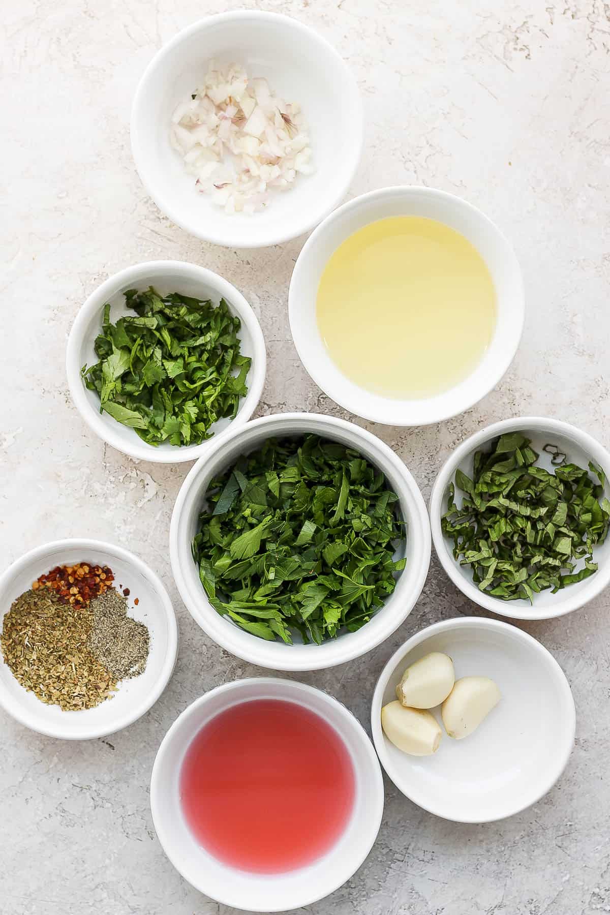Ingredients for chimichurri sauce in separate bowls.