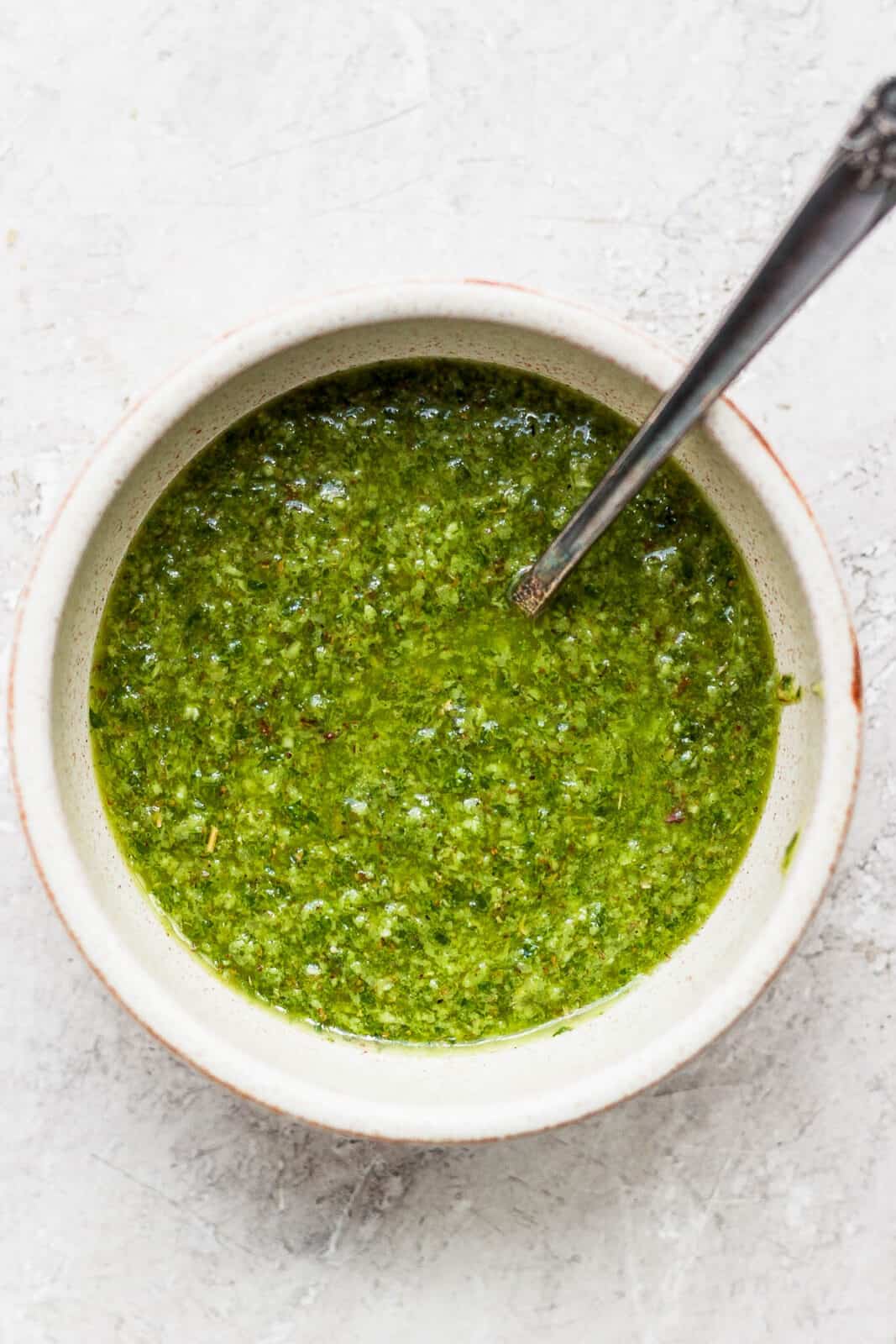 Traditional chicmichurri sauce in a bowl with a spoon.