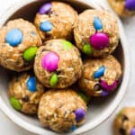 Bowl of no bake energy balls with different colored chocolate candies in them.