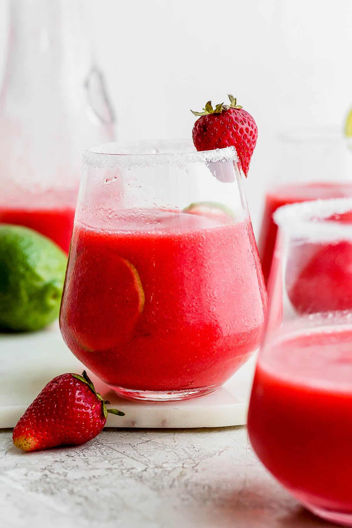 A frozen strawberry margarita with a strawberry garnish.