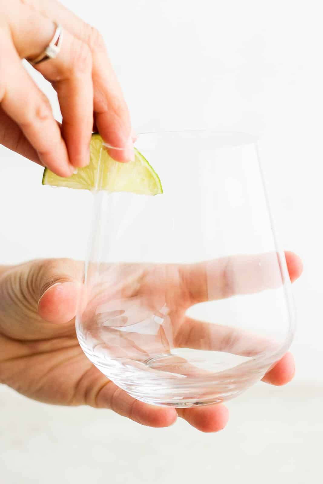 The rim of a glass being rubbed with a lime wedge.
