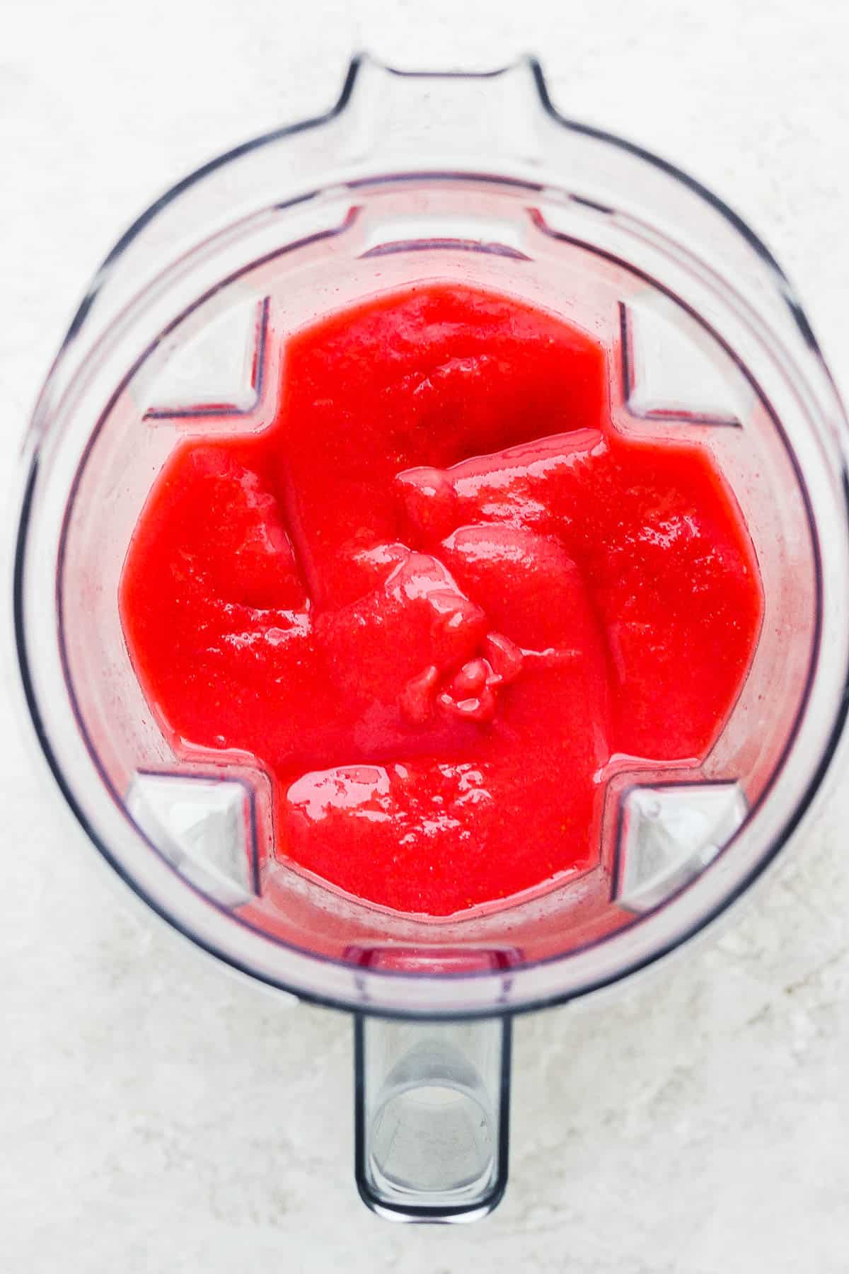 Blended frozen strawberry margaritas in a blender.