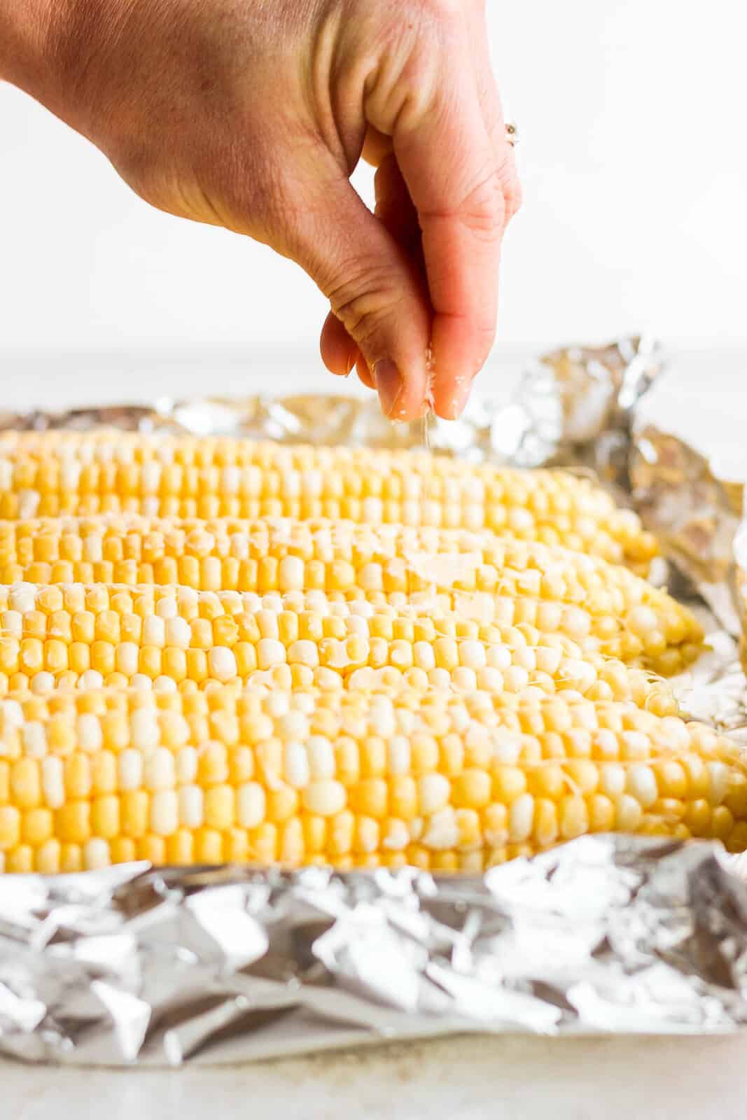 Corn on the cob sprinkled with kosher salt while laying on top of heavy duty foil. 