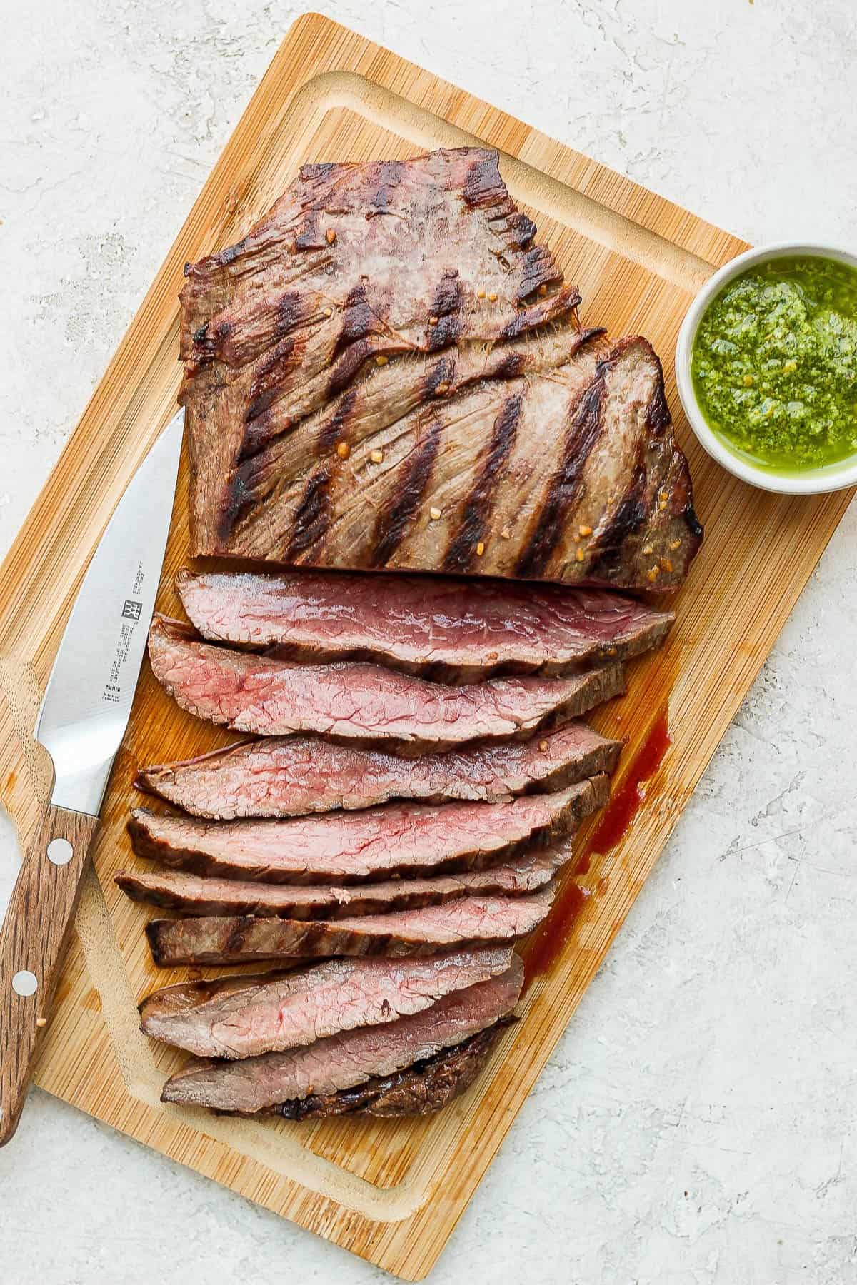 A grilled flank steak resting on a cutting board.