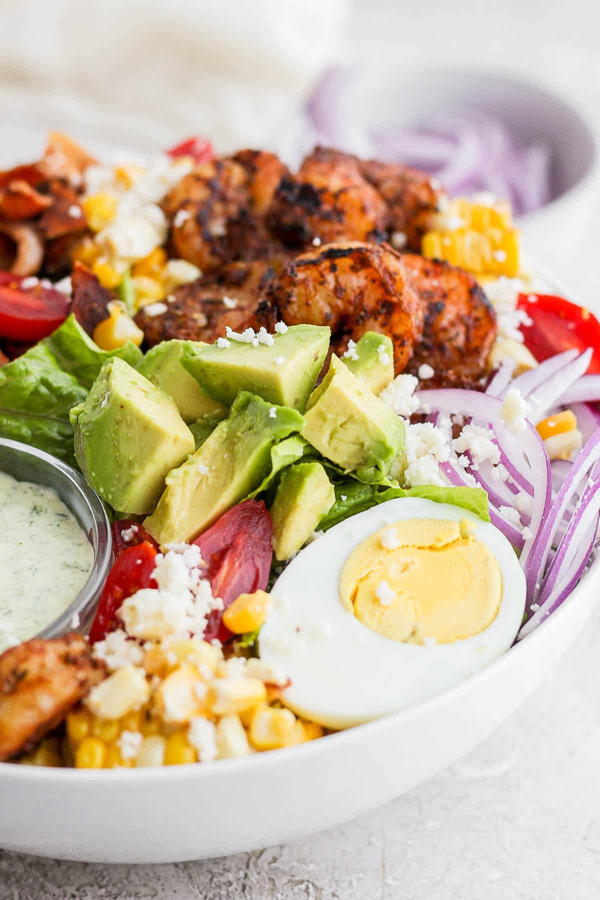 A grilled shrimp salad in a white bowl.