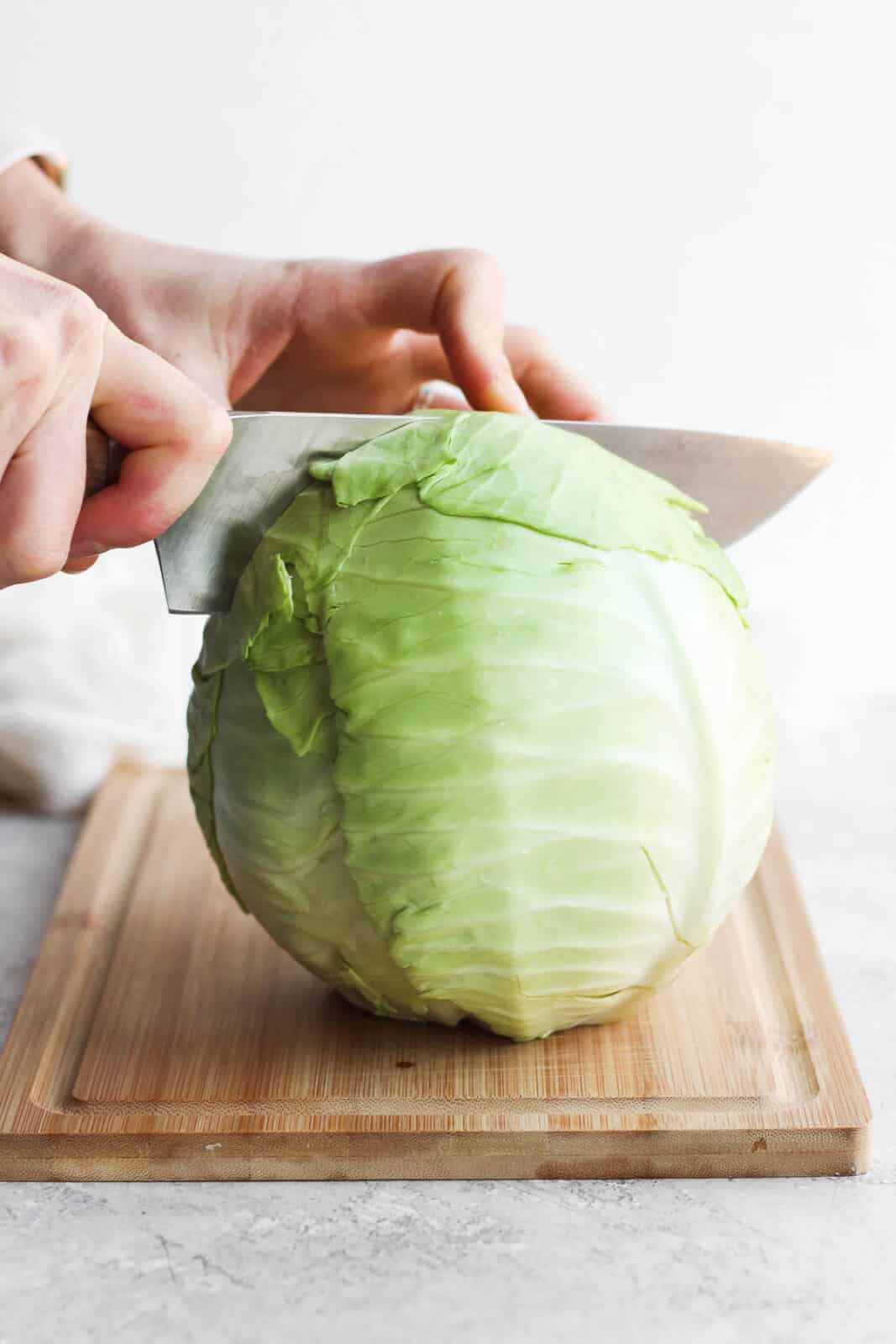 A large knife cutting a cabbage in half.