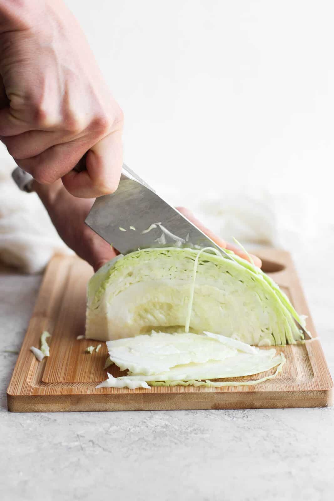 A large knife slicing the cabbage into thin strips.