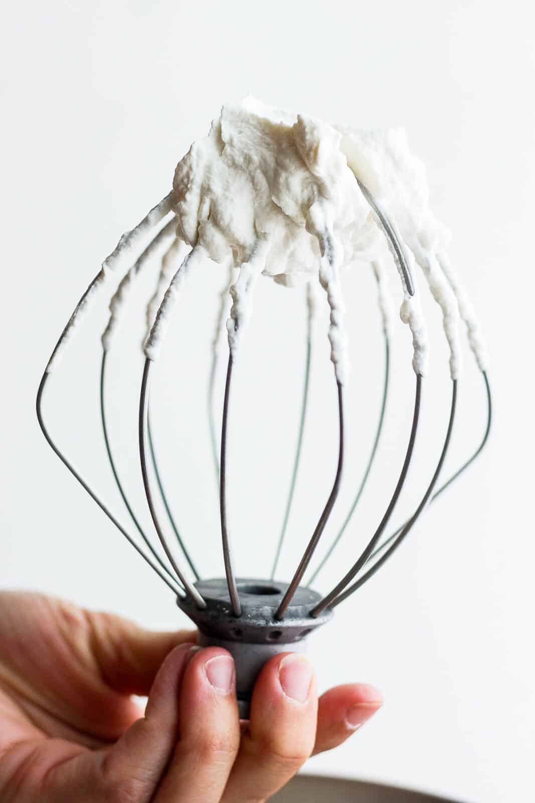Homemade whipped cream on a whisk attachment for a stand mixer.