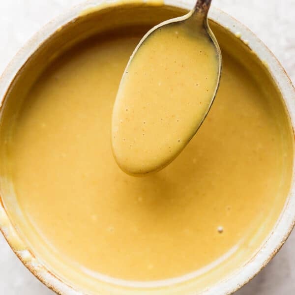Bowl of honey mustard with a spoon scooping some out.