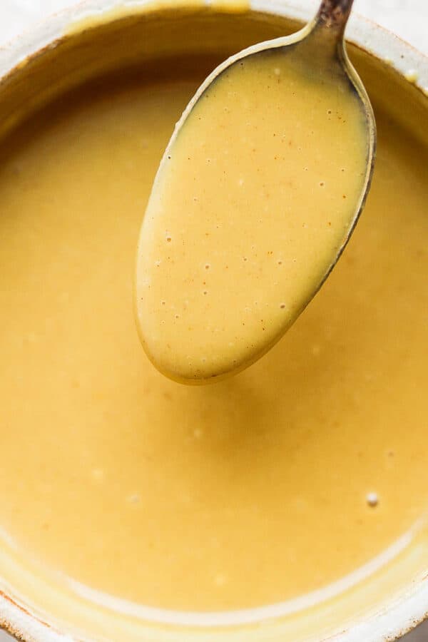Bowl of honey mustard with a spoon scooping some out.