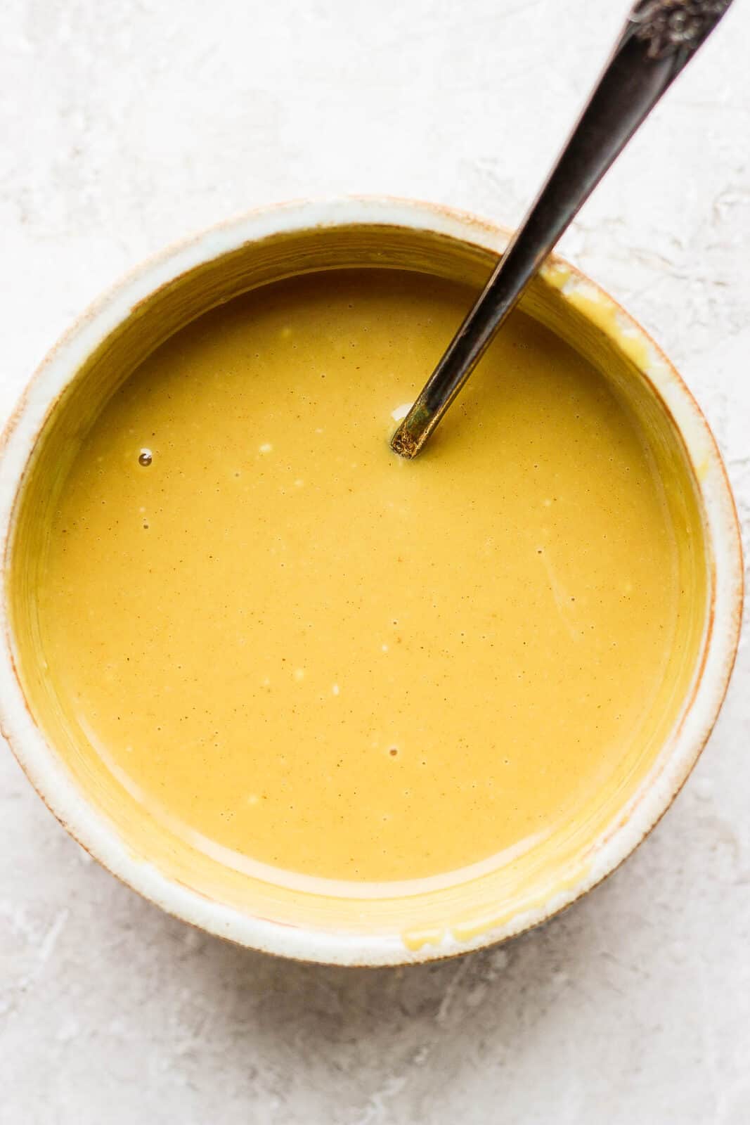 Homemade honey mustard in a bowl with a spoon.