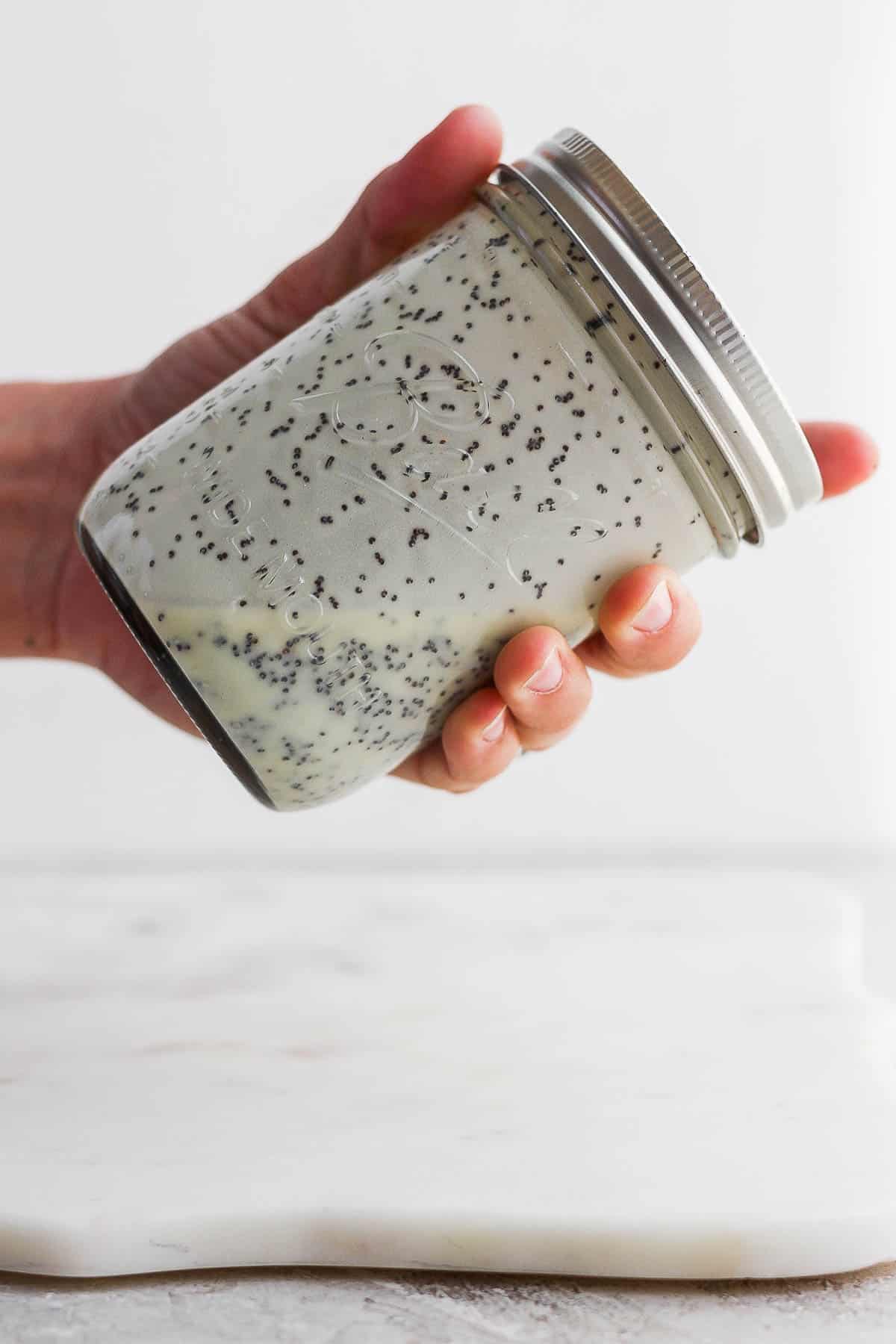 Homemade poppyseed dressing being shaken in a mason jar.