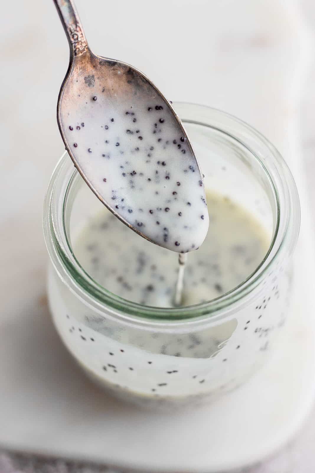 Homemade poppyseed dressing running off a spoon into a jar.