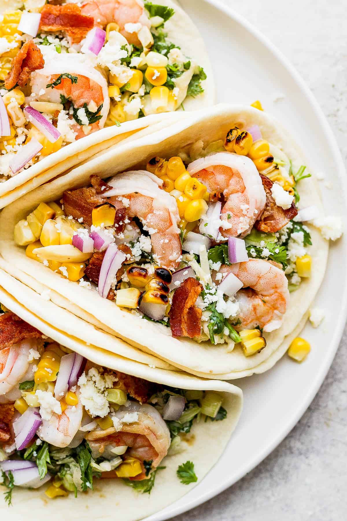 Close up of a plate of three shrimp tacos. 