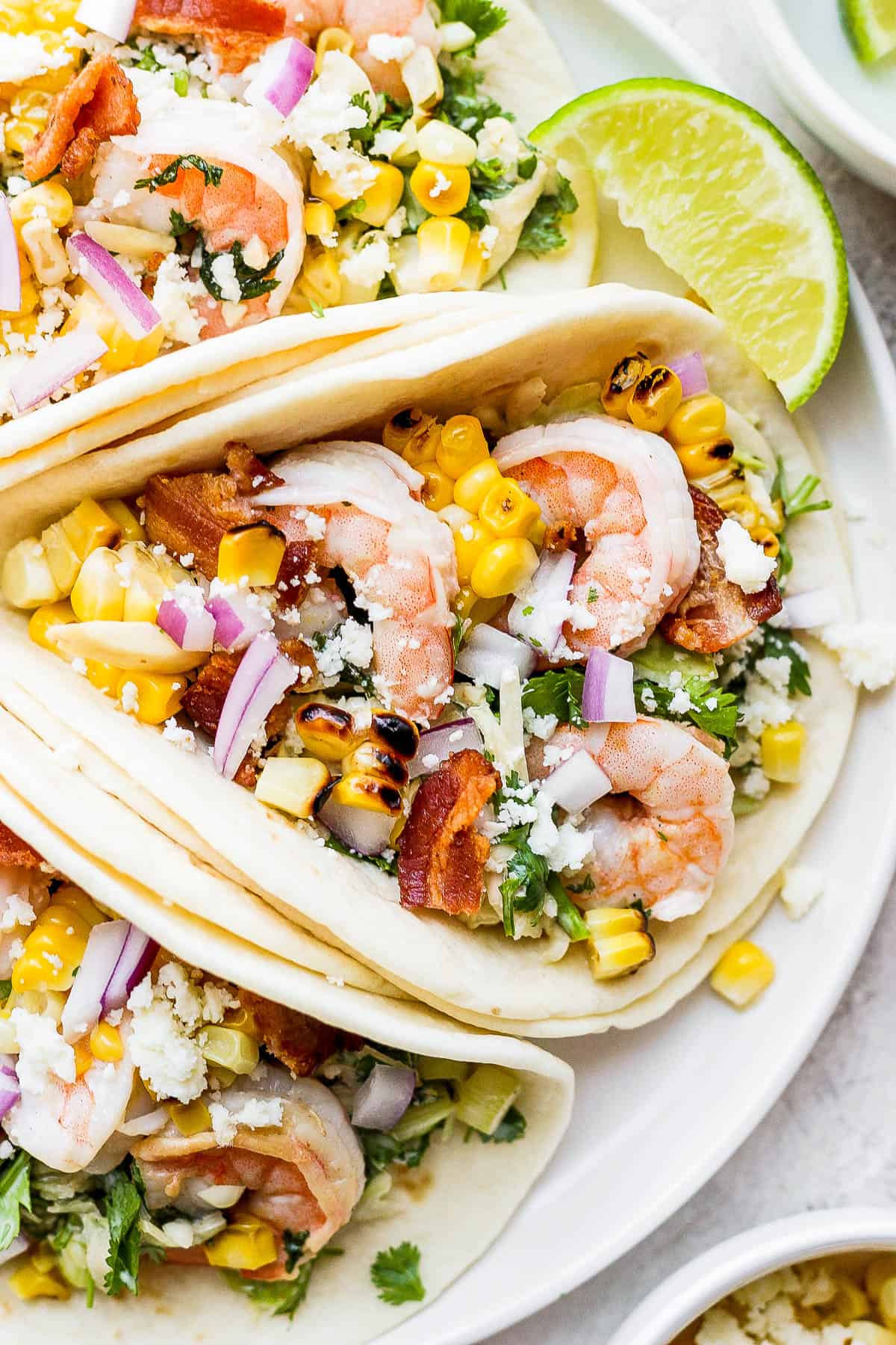 A close up of a plate of three shrimp tacos. 