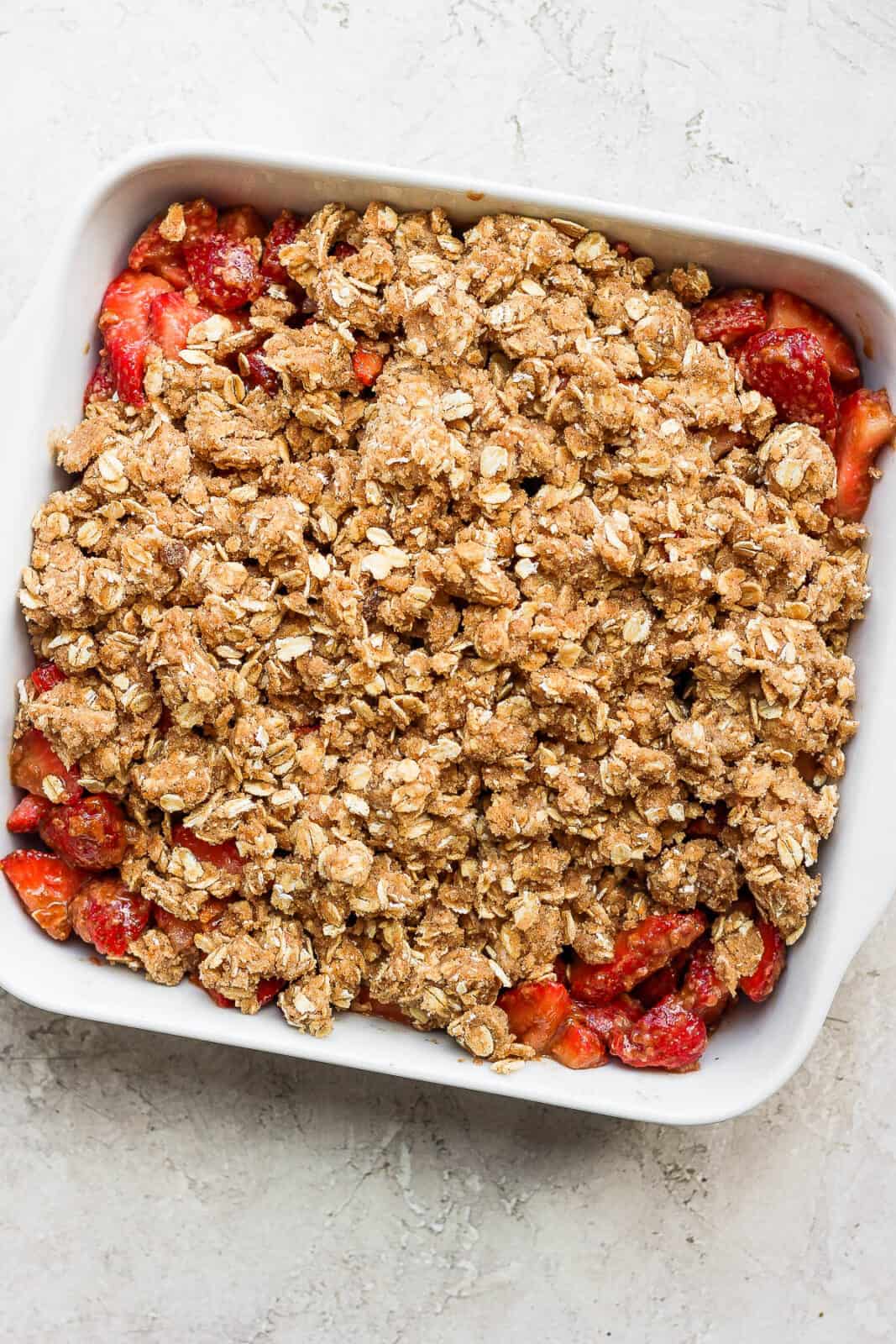 Oat topping on top of the strawberries in a baking dish.
