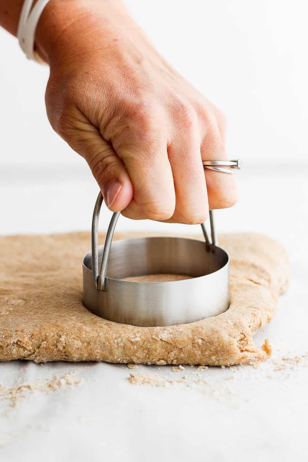 A biscuit cutter cutting the shortcake dough into circles.