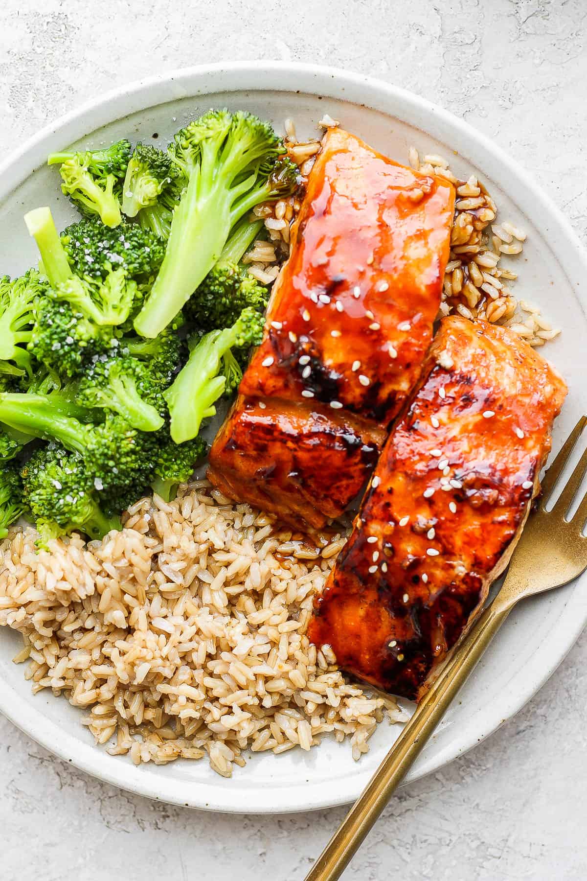 A plate of teriyaki salmon, brown rice and broccoli.