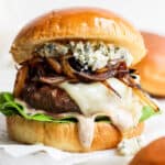 A bison burger on a bun with melted cheese, whiskey onions and gorgonzola cheese.