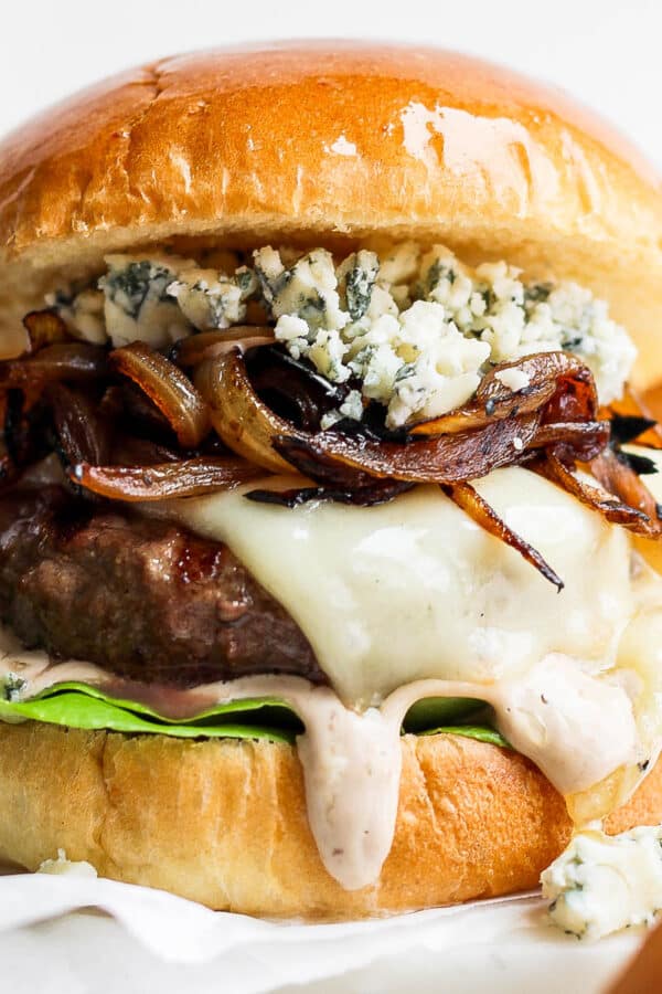 A bison burger on a bun with melted cheese, whiskey onions and gorgonzola cheese.