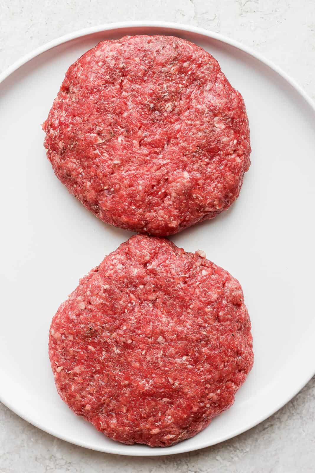 Two bison burger patties on a plate.