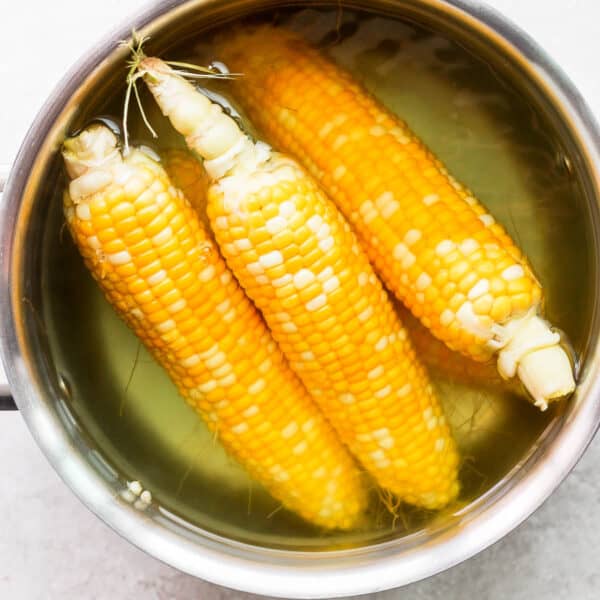 A pot of water with corn being boiled in it.