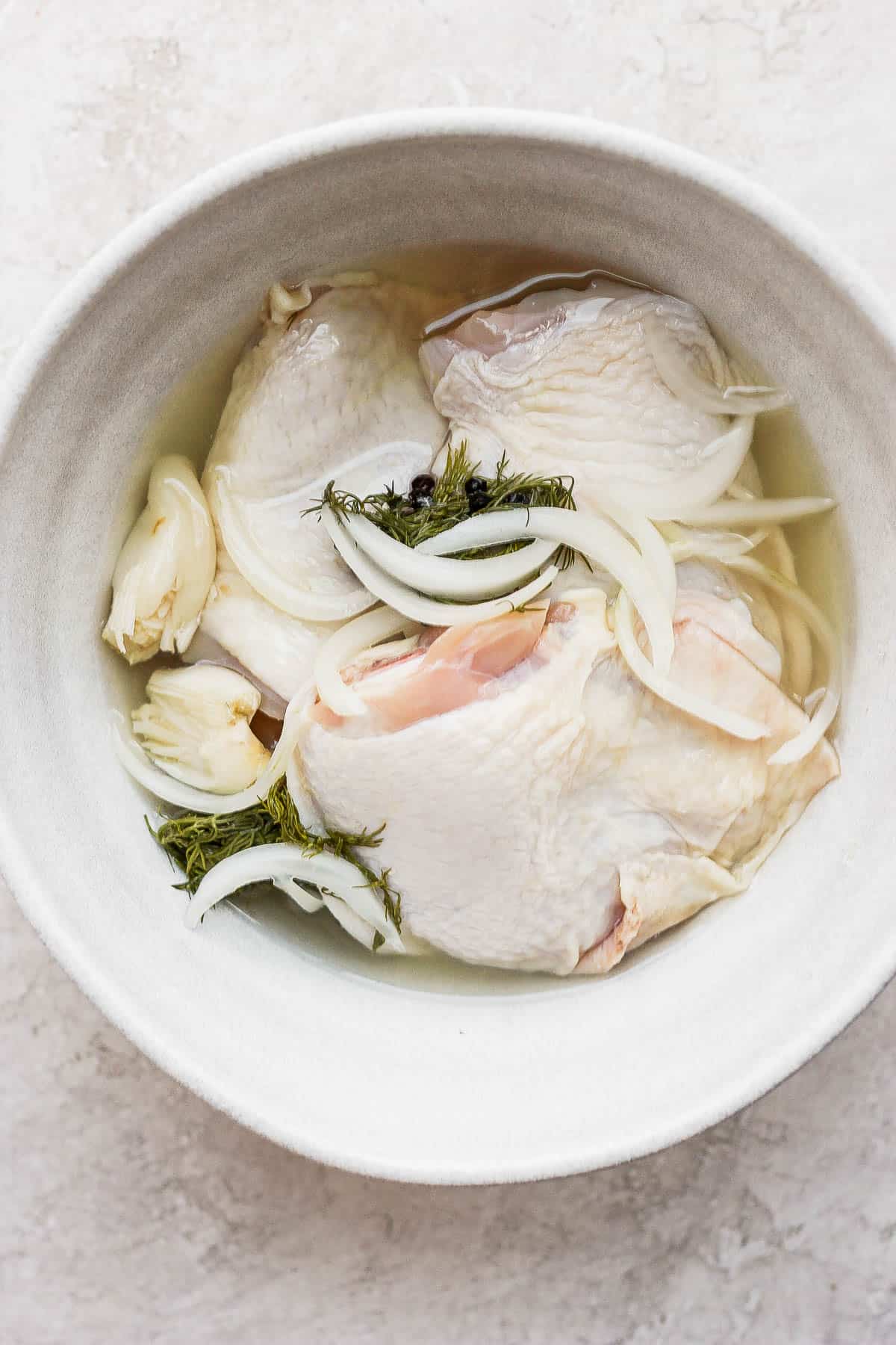 Chicken thighs in a large bowl with pickle juice.