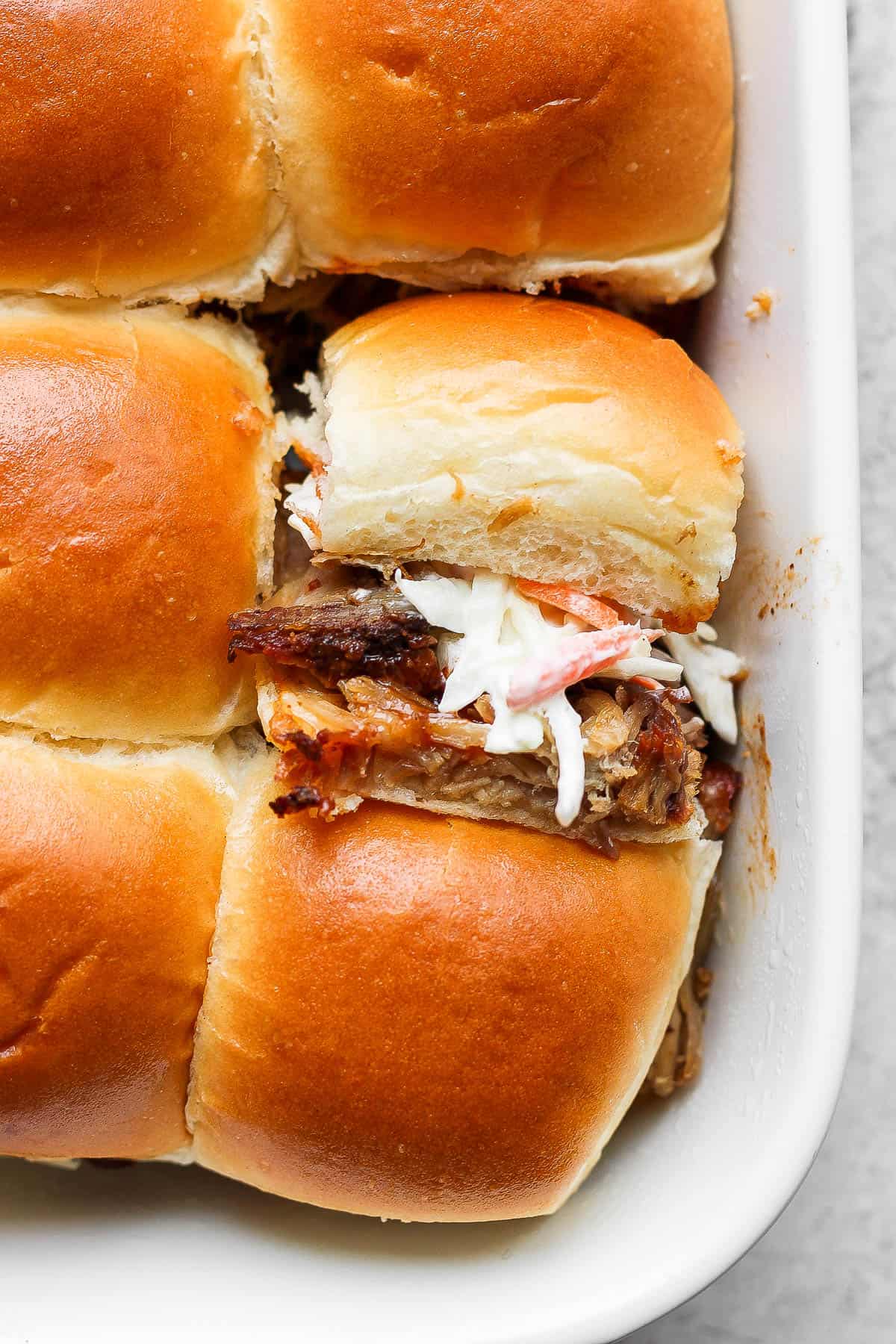 Pulled pork sliders in a baking dish.