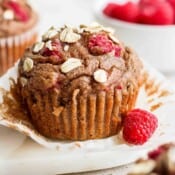 A raspberry muffin with a fresh raspberry next to it.