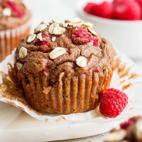 A raspberry muffin with a fresh raspberry next to it.