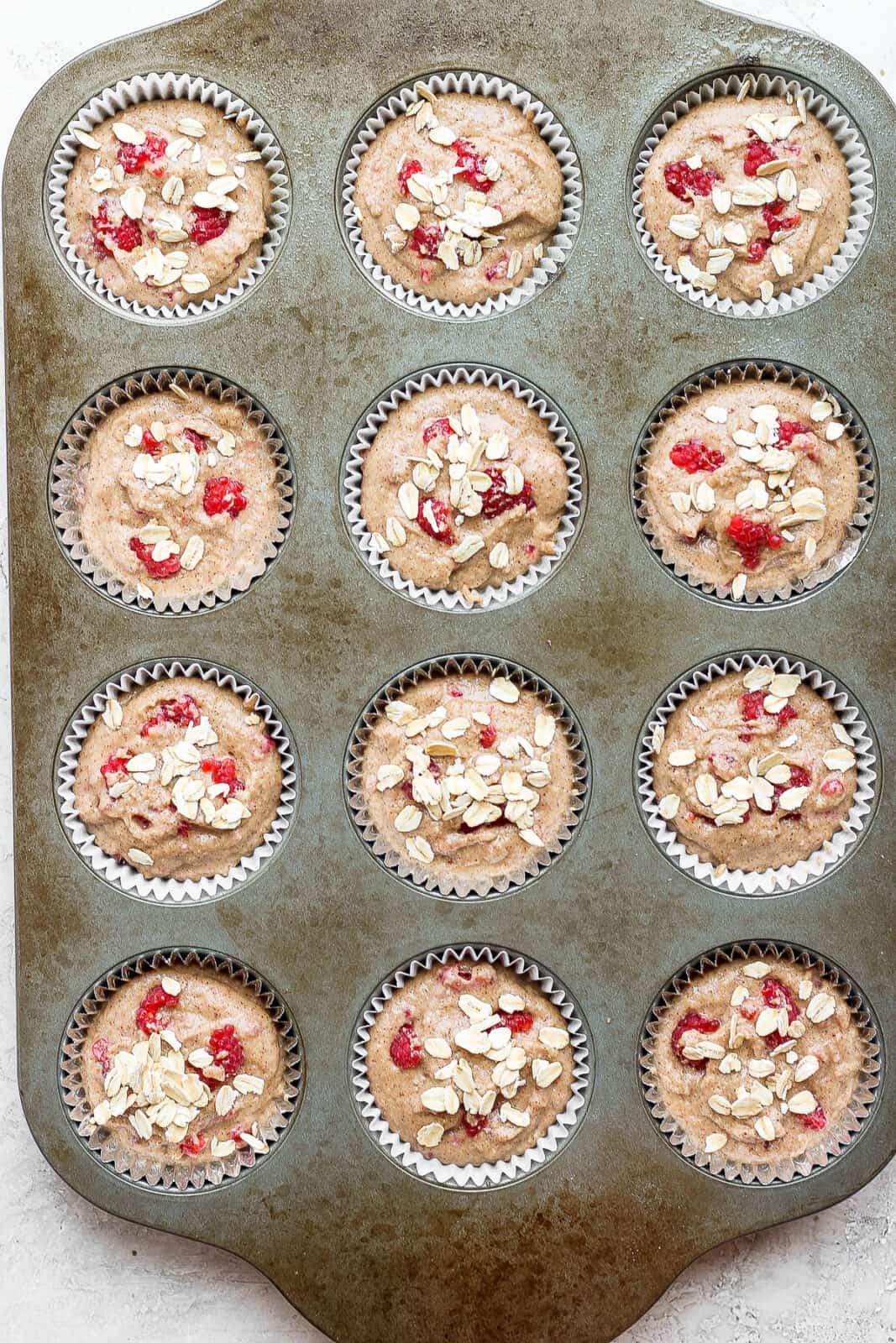 Raspberry muffins in a muffin tin before baking.