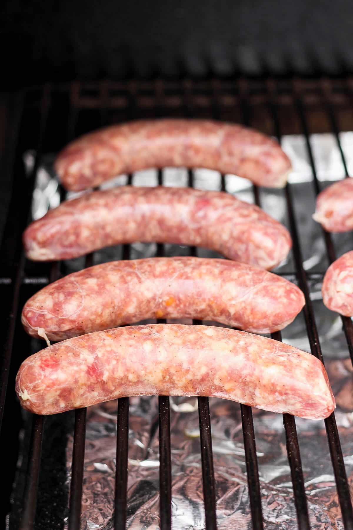 Raw brats on a smoker.