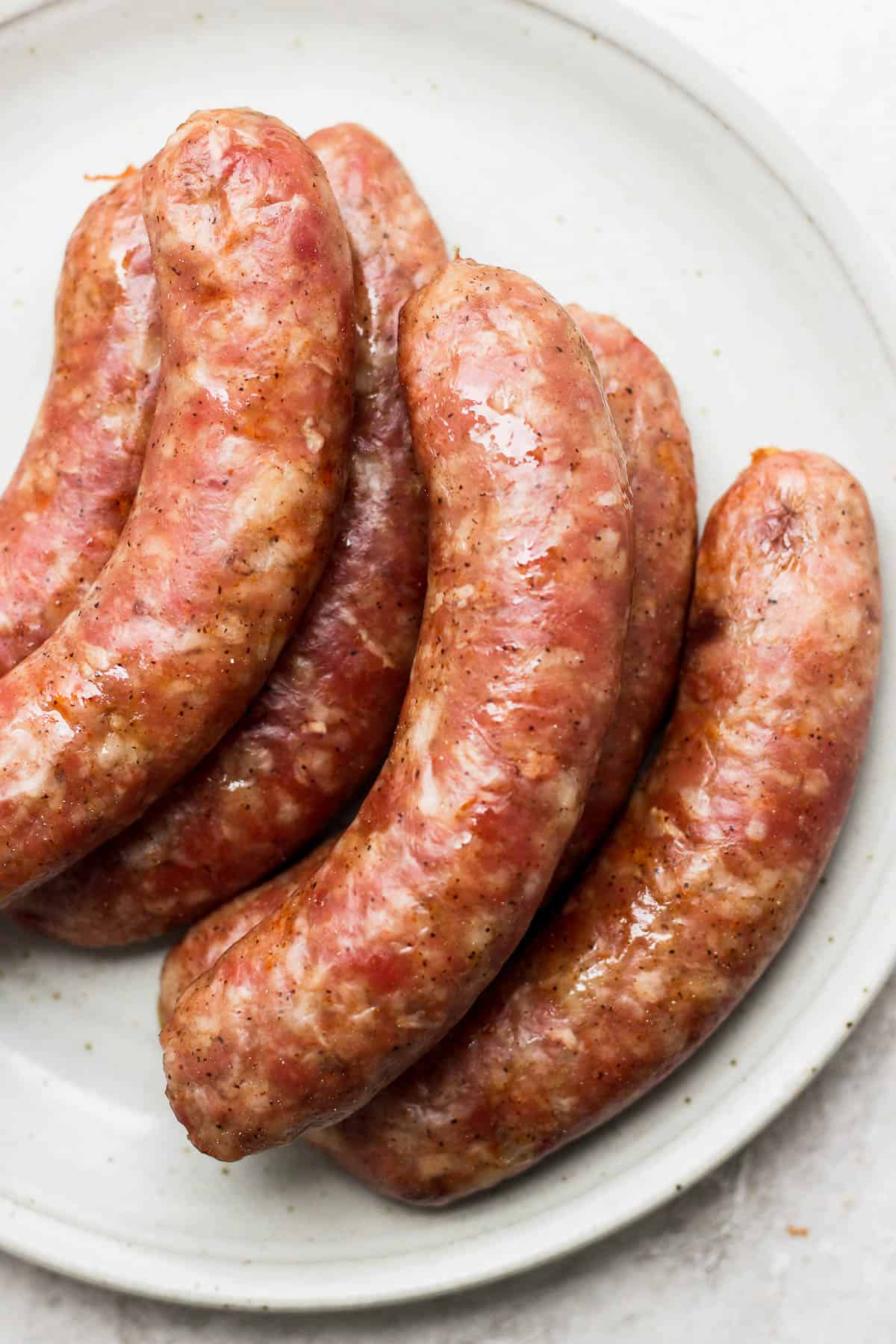 Brats resting on a plate.