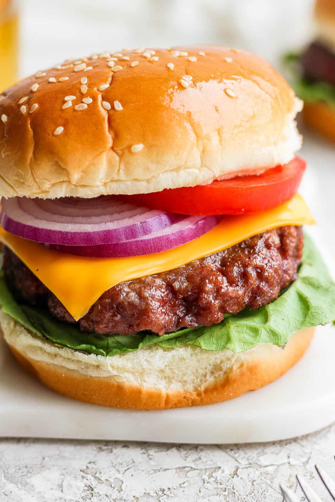 A smoked burger on a bun with lettuce, cheese, onion and tomato. 