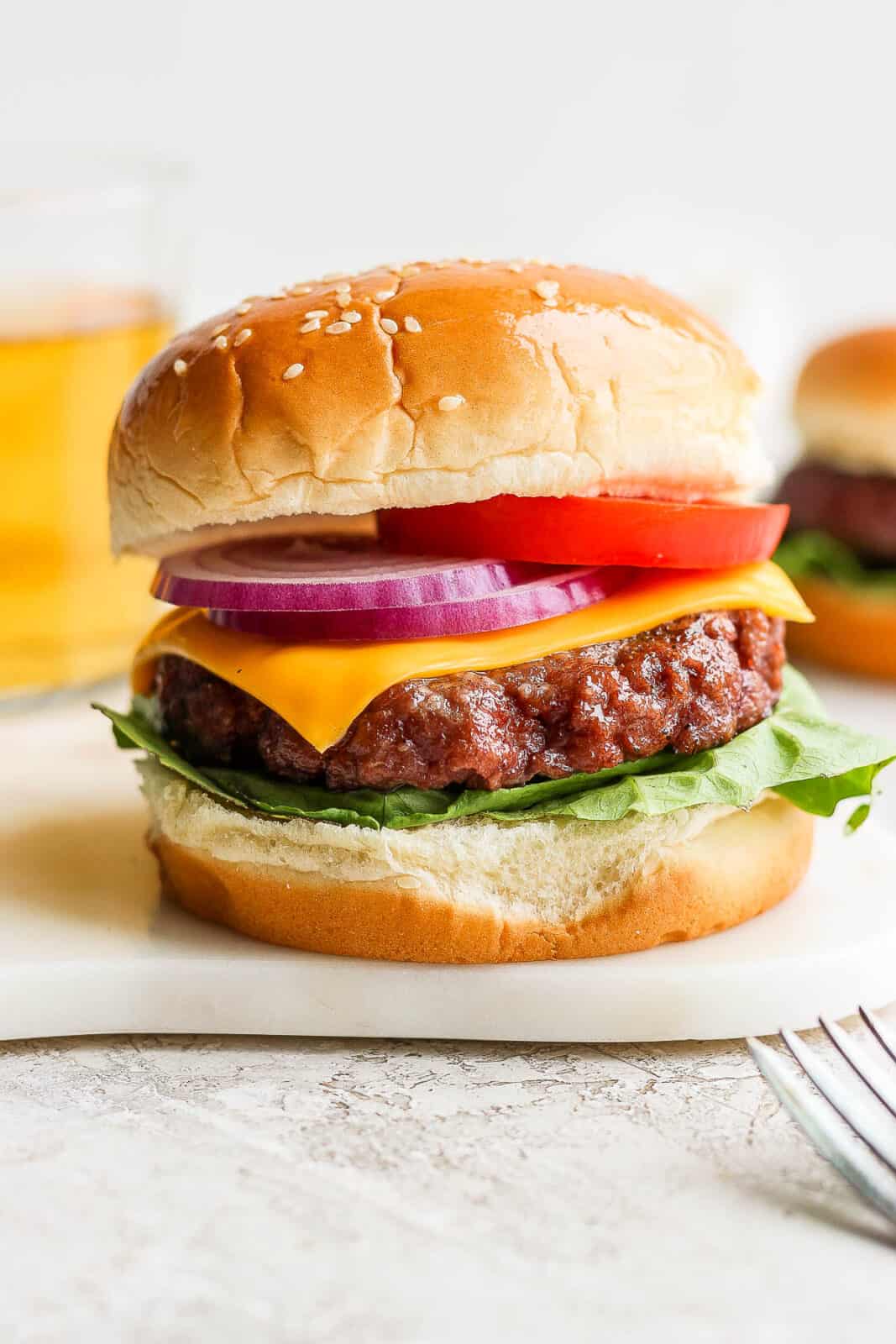 A smoked burger on a bun with lettuce, cheese, onion and tomato. 